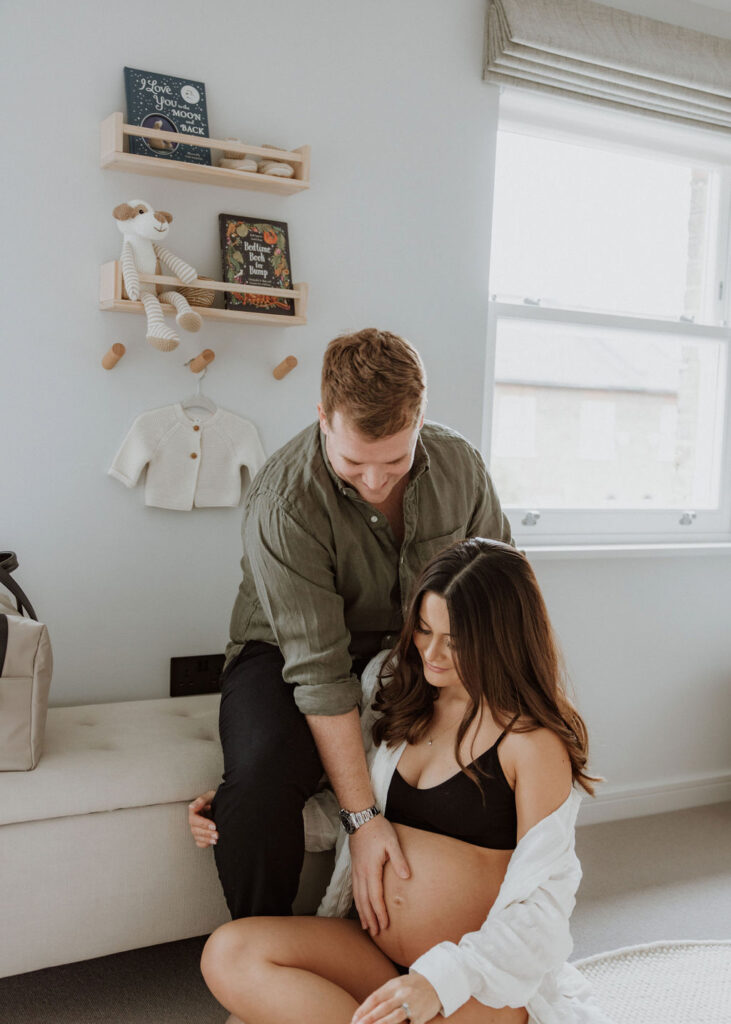 Couple embracing baby bump during intimate in-home maternity photography in London living room