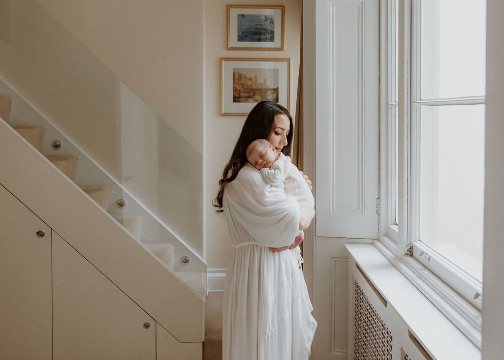 Mother cradling newborn baby in her arms during intimate in-home newborn session