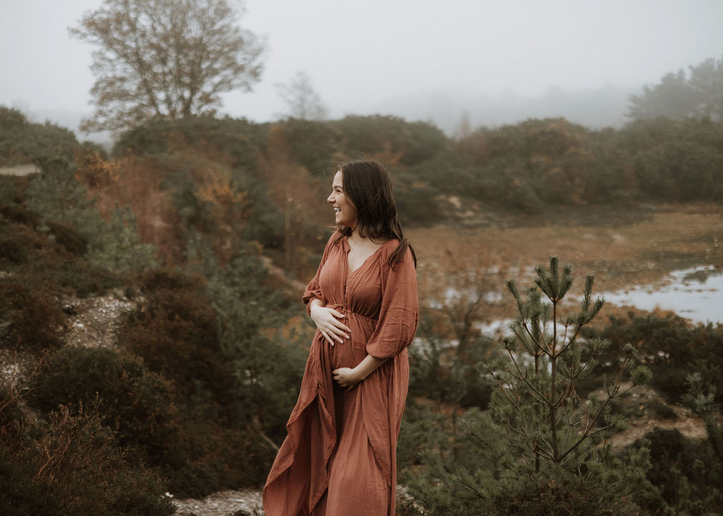 Expectant mother in flowing dress during outdoor maternity session in Surrey woodland