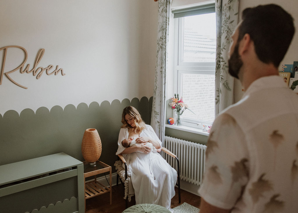 Proud father watching mother with newborn during photography session