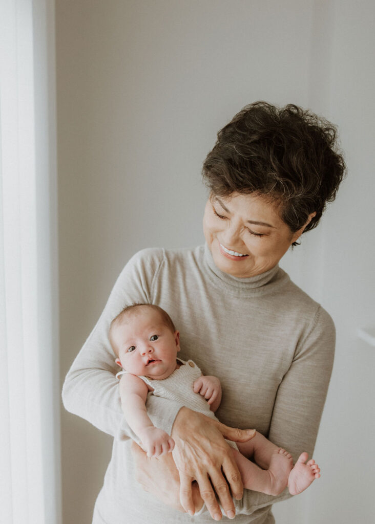 A grandmother gently holding her newborn grandchild, preserving a multi-generational bond in this heartfelt newborn session