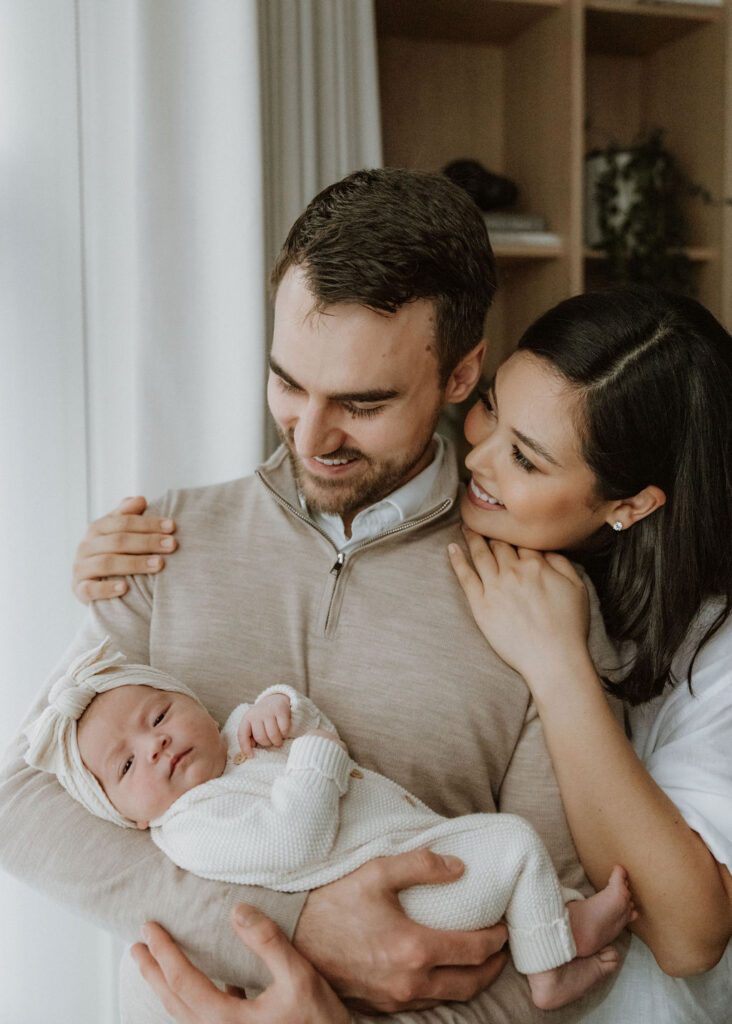 A candid moment of parents snuggling their newborn in their East Dulwich home, capturing the deep connection between them